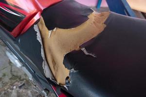 lacerated motorcycle seat , Old Black Leather seat is damage , Broken leather. photo