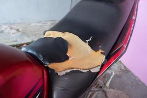 asiento de motocicleta lacerado, asiento de cuero negro viejo dañado, cuero roto. foto