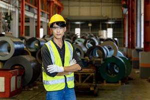 Portrait of asian engineer worker is examining the stainless galvanized metal sheet roll inside the warehouse factory for roofing industry photo