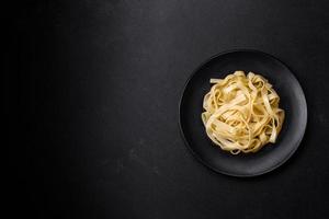 Delicious fresh pasta with pesto sauce and seafood on a black plate photo