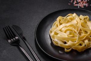 Delicious fresh pasta with pesto sauce and seafood on a black plate photo