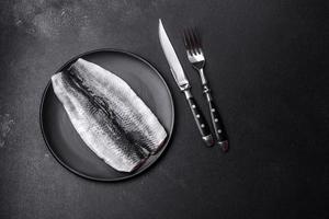 Marinated fillet with spices and herbs of sea herring on a black plate photo