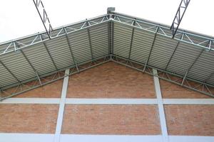 Warehouse roofing built on brick wall facade. photo