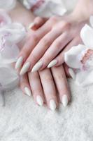 Hands of a young woman with white manicure on nails photo