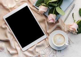 vista superior de una taza de café latte art en forma de corazón con una rosa rosa y una tableta foto