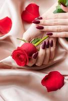 Hands of a young woman with dark red manicure on nails photo