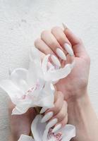 manos de una mujer joven con manicura blanca en las uñas foto