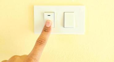 interruptor de luz blanca, presionar con el dedo, el concepto de ahorro de electricidad, reducción de costos. foto