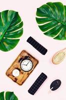 Alarm clock with tropical leaves on pink background. photo