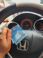 Jakarta, Indonesia on July 2022. A hand is holding a fifty thousand rupiah bill which bends while driving. photo