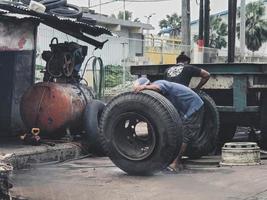 Jakarta, Indonesia in July 2022. Two men were replacing a blown truck tire. photo