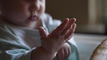 rommelig baby meisje aan het eten voedsel in hoge stoel video