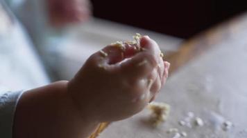 de hand- van een rommelig baby meisje aan het eten voedsel video