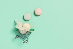 Mint background with shopping cart and marshmallows. photo