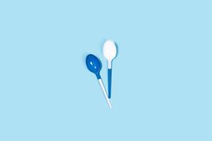 Two plastic spoons on blue background. photo