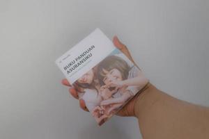 West Java, Indonesia on July 2022. A hand holding Manulife's Insurance Handbook for life and health insurance photo