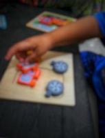 Defocused blurry shot of a boy's hand holding a wooden puzzle photo