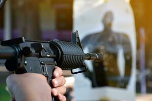 Airsoft Gun or BB Gun holding in hands of shooter while aiming to the destination target at the bb gun or airsoft gun training camp, soft and selective focus, concept for freetimes and outdoor hobby. photo