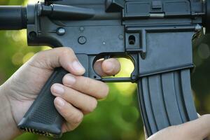 Airsoft Gun or BB Gun holding in hands of shooter while aiming to the destination target at the bb gun or airsoft gun training camp, soft and selective focus, concept for freetimes and outdoor hobby. photo