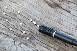 BB gun or airsoft gun muzzle and white bullets on wooden plank, soft and selective focus. photo