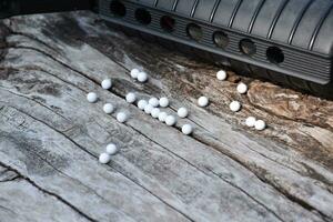 BB gun or airsoft gun muzzle and white bullets on wooden plank, soft and selective focus. photo