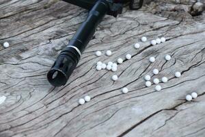 BB gun or airsoft gun muzzle and white bullets on wooden plank, soft and selective focus. photo