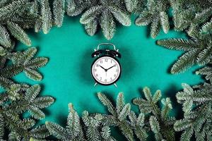 reloj negro sobre fondo verde con ramas de navidad. foto