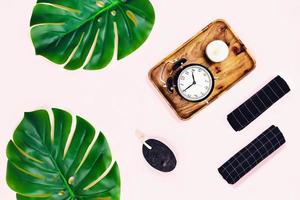 Alarm clock with tropical leaves on pink background. photo