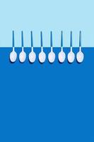 Picture of white plastic spoons on blue background. photo