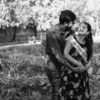 Indian couple posing for maternity baby shoot. The couple is posing in a lawn with green grass and the woman is falunting her baby bump in Lodhi Garden in New Delhi, India photo