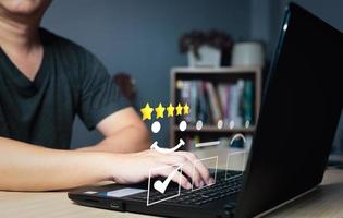 a businessman use computer laptop choose on the happy smile face icon to give satisfaction in service.rating very impressed.Customer service and Satisfaction concept photo