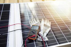 Multimeter and glove pictured on solar panel photo