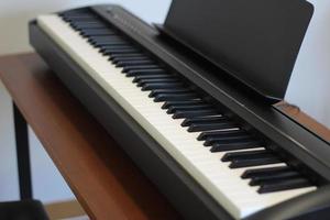 Black piano keyboard with white keys against window interior background photo