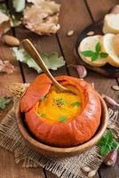 Pumpkin cream soup with peppers and herbs in a pumpkin photo