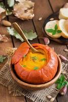 sopa de crema de calabaza con pimientos y hierbas en una calabaza foto