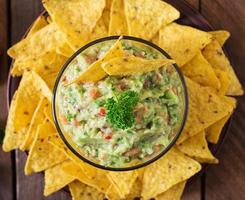 aguacate guacamole, lima, tomate, cebolla y cilantro, servido con nachos - merienda tradicional mexicana foto