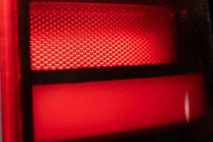 fondo rojo - detalle de una luz roja de advertencia de tráfico. el conjunto de luces de freno de un automóvil moderno foto