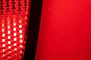 red background - detail of a red traffic warning lamp. The brake light assembly of a modern automobile photo