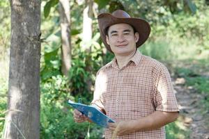 Portrait of Asian male botanist is inspecting and recording about tree information on paper clipboard.Concept , Survey ,research botanical plants. Forest and environment conservation. photo