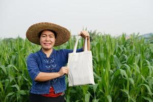 retrato de mujer agricultora asiática usa sombrero, sostiene una bolsa en el jardín. concepto, campaña para usar bolsas de algodón en lugar de bolsas de plástico para detener la basura plástica. bolsa de reutilización para el medio ambiente foto