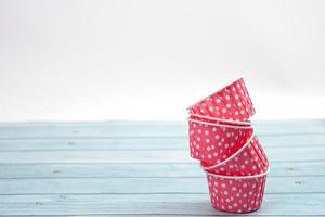 Pink polka dot cupcake cases on blue wooden floor. Material for baking.