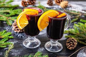 Glass of delicious glintwein or mulled hot wine, cinnamon, thread on vintage wooden background. photo