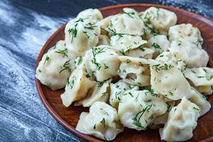 Traditional russian pelmeni or ravioli, dumplings with meat on wood black background. Russian food and russian kitchen concept. photo