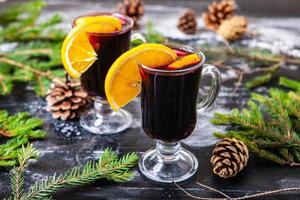 Glass of delicious glintwein or mulled hot wine, cinnamon, thread on vintage wooden background. photo