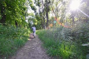 A young guy in a gray sports suit runs along the path among the photo