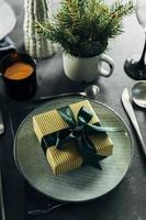 Christmas or New Year Table Setting. Craft blue plate with cutlery and gift box, fir tree branches
