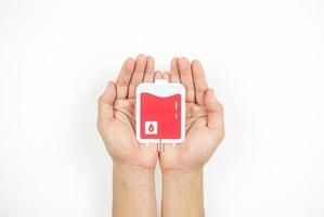 Hands holding blood pack paper cut on white background, Blood transfusion, World blood donor day. Blood Donation and Saving life Concept photo