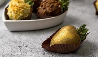 Closeup of a chocolate strawberry painted golden. Dessert concept photo