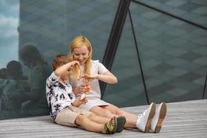 Happy blond woman and little boy sitting on terrace and eating sweets. Mother and son enjoy time together. Positive young mom playing, spending time with her cute child, laughing, having fun. Family. photo