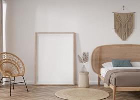 Empty vertical picture frame standing on parquet floor in modern bedroom. Mock up interior in boho style. Free space for picture or poster. Bed, macrame, rattan armchair, pampas grass. 3D rendering. photo